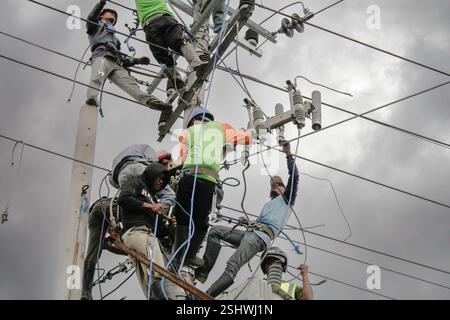 Gruppe von Elektroarbeitern, die Wartungsarbeiten an Hochspannungsleitungen in einem bedeckten Außenbereich in Indonesien durchführen Stockfoto
