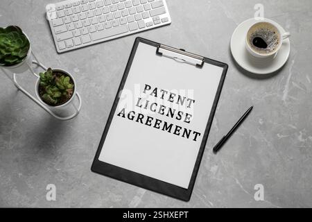 Papier mit Text der Patentlizenzvereinbarung, Stift, Kaffee und Computertastatur auf grauem Tisch, Draufsicht Stockfoto