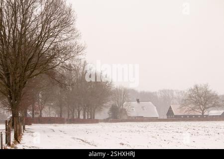 Bauernhof im Hintergrund, ein Weg zwischen den Wiesen, bedeckt mit Schnee, Winter Stockfoto
