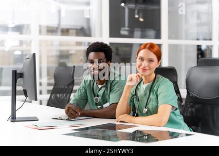 Multiethnische Gruppe von Fachkräften im Gesundheitswesen, die in der Klinik zusammenarbeiten und ihre Expertise austauschen Stockfoto