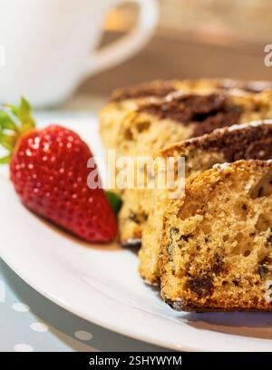 Marmorkuchen mit Rosinen und Walnüssen. Ein Stück Kuchen auf einem Teller mit einer Erdbeere. Stockfoto