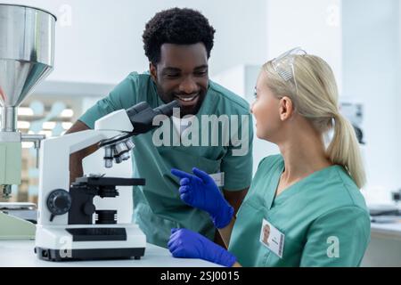 Forscherin arbeitet mit verschiedenen Kollegen im Biologielabor mit Mikroskop zusammen Stockfoto