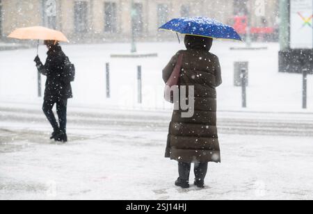 Hannover, Deutschland. Februar 2025. Zwei Frauen stehen mit Sonnenschirmen im Schnee im Stadtzentrum. Quelle: Julian Stratenschulte/dpa/Alamy Live News Stockfoto