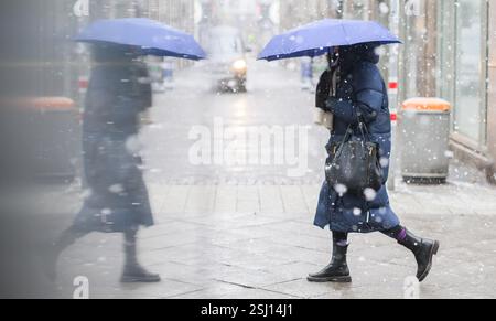 Hannover, Deutschland. Februar 2025. Eine Frau mit einem Regenschirm wird während des Schneefalls in der Glasscheibe eines Vitrinenregals reflektiert. Quelle: Julian Stratenschulte/dpa/Alamy Live News Stockfoto