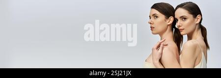 Zwei hübsche Zwillingsschwestern stehen eng zusammen und zeigen ihre natürliche Schönheit und Eleganz. Stockfoto