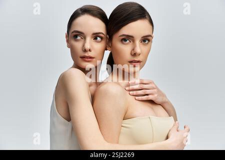 Zwillingsschwestern teilen einen zärtlichen Moment und zeigen ihre Schönheit und tiefe Verbundenheit. Stockfoto