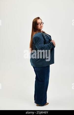 Eine junge, schöne Frau in Übergröße präsentiert ihr Outfit in einem gut beleuchteten Raum mit Selbstvertrauen. Stockfoto