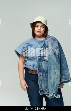 Eine junge Frau in Übergröße präsentiert zwei Denim-Jacken in einer trendigen Mode. Stockfoto