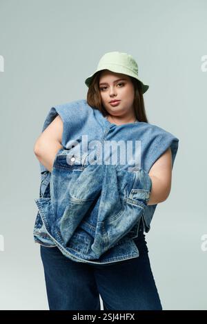 Eine junge Frau in Übergröße zeigt ihr Gespür für Mode und posiert spielerisch in Jeansbekleidung. Stockfoto