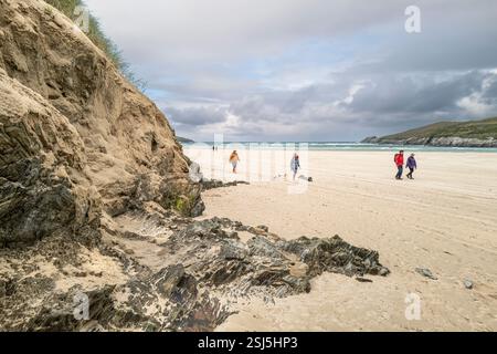 Menschen, die an dem instabilen Sanddünen-System am Crantock Beach in Newquay in Cornwall in Großbritannien vorbeilaufen. Stockfoto