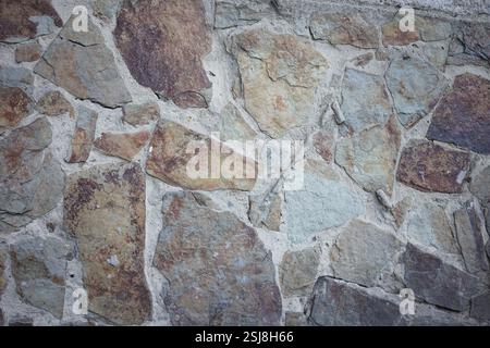 Die Nahaufnahme zeigt eine aufwändig gemusterte Steinmauer mit verschiedenen Grau-, Braun- und Beigetönen. Natürliche Mineralien und Texturen schaffen eine St Stockfoto