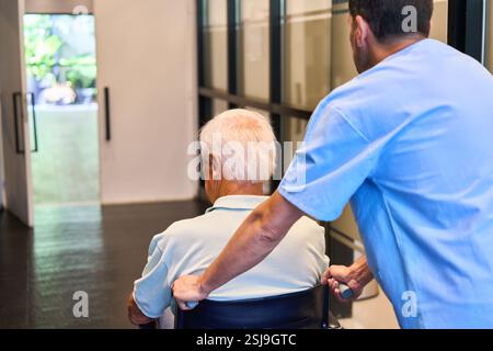 Ein Pflegefachmann hilft einem älteren Menschen in einer Gesundheitseinrichtung, die Rehabilitationsdienste für Senioren, die Pflege und zeigen Stockfoto