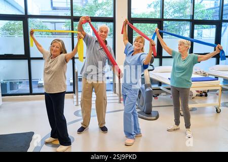 Ältere Teilnehmer, die eine von einem Fachmann geführte Therapieübung in einem Rehabilitationszentrum durchführen, um Wellness, Mobilität und körperliche HE zu fördern Stockfoto