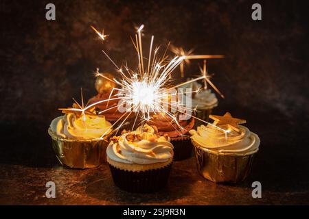Hausgemachte Cupcakes mit weißer Buttercreme auf braunem marmoriertem Hintergrund und einem leuchtenden Funkeln im Querformat Stockfoto