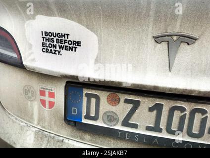 Auf dem Aufkleber auf einem dreckigen TESLA-Auto mit deutschem Kennzeichen steht, dass ich DAS AUFTAUCHE, BEVOR ELON VERRÜCKT WURDE. Stockfoto