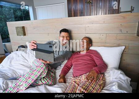 Schwules Paar mit Tablet im Bett Stockfoto