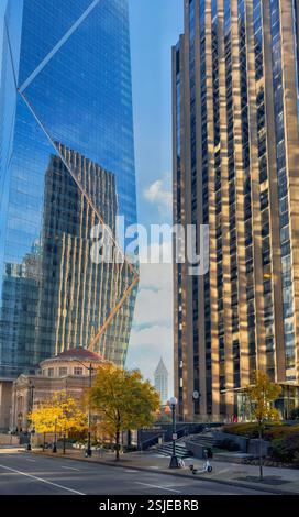 Das Bild zeigt eine Straße in Seattle, die von hohen Wolkenkratzern gesäumt ist, deren Glasfassaden den blauen Himmel und die umliegenden Gebäude reflektieren. Stockfoto