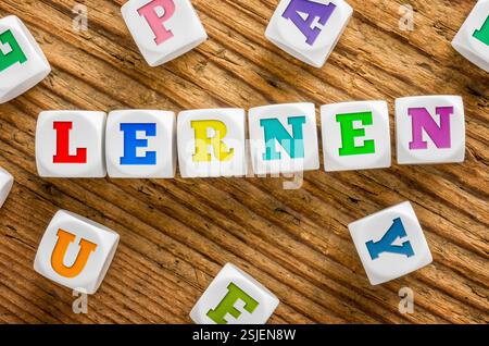 Buchstabenwürfel auf hölzernem Hintergrund - Lernen Stockfoto