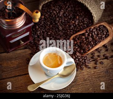 Tasse Espresso-Kaffee, Kaffeebohnen und alte Kaffeemühle auf dem Holztisch. Stockfoto