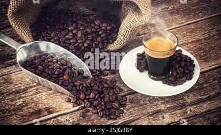 Espresso Kaffee in Glastasse mit Kaffeebohnen auf Holztisch. Stockfoto
