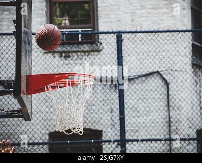 Basketballkorb auf einem Spielplatz in New York. Der Ball prallt vom Spielbrett ab und ist bereit für den Eintritt. Stockfoto
