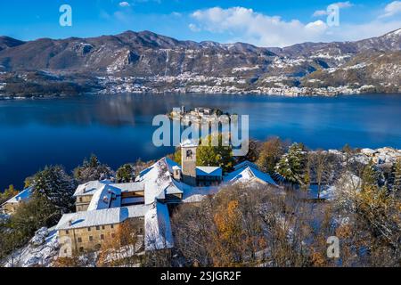 Aus der Vogelperspektive auf den Sacro Monte von Orta und die Insel San Giulio auf dem See Orta im Winter nach einem Schneefall. Orta Lake, Provinz Novara, Piemont, Italien. Stockfoto