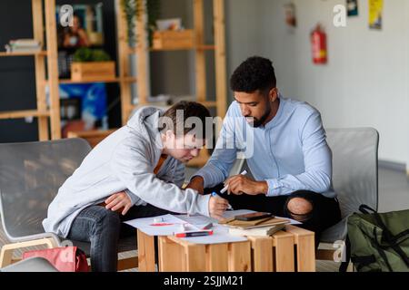 Junger Mann mit Down-Syndrom-Studyng mit Sonderpädagogin im Sonderunterricht. Stockfoto