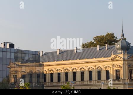 An der modernen Glasfassade eines anderen Gebäudes sind die Reflexionen eines historischen Gebäudes zu sehen. Stockfoto