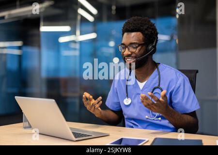 Erfolgreicher erfahrener Arzt mit Headset und Laptop im Büro am Arbeitsplatz, der Remote arbeitet. Man berät Patienten, hilft und unterstützt, Videoanrufe, Fernkonferenzen. Stockfoto