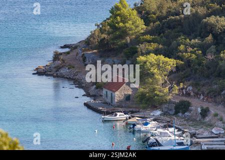 Ruhiges Küstenhaus an einer ruhigen Bucht mit Booten und grüner Vegetation, perfekt zum Entspannen und Erkunden. Stockfoto