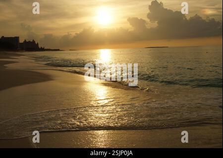 Sonnenuntergang am Strand auf Bahamas. Die goldene Sonne taucht unter den Horizont und strahlt ein warmes Leuchten über das ruhige Meer und die Sandküste. Friedlicher Moment der Ruhe und Stockfoto