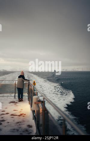 Frau beobachtet Boot auf dem arktischen Ozean im Fjord bei Tromso, Norwegen Stockfoto