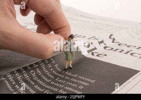 Hand, die eine menschliche Figur auf eine Zeitung Stockfoto