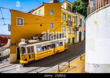 LISSABON, PORTUGAL - 11. Juni 2024: Alte gelbe Straßenbahn Nr. 28 während seiner Reise mit Touristen durch die Altstadt von Lissabon, Bezirk Alfama. Stockfoto
