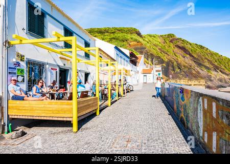 STADT HORTA, INSEL FAIAL - 12. Juni 2024: Touristen, die Getränke und Snacks in der Küstenbar in der Nähe des Strandes Porto PIM auf den Azoren, Portugal genießen. Stockfoto