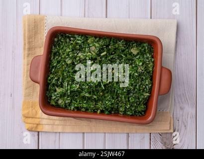 Gekochte Grünkohl-Streifen, typisch brasilianische Feijoada-Beilage auf einem Teller über Holztisch. Stockfoto