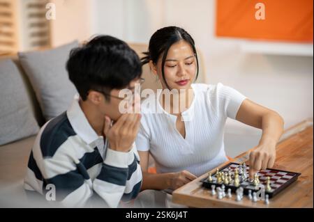 Zwei glückliche asiatische Freundinnen und Freundinnen spielen gemeinsam Schach im Wohnzimmer. Freizeitaktivität, Unterhaltung, Brettspiel Stockfoto