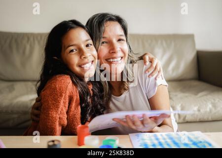 Familie, glückliche Mutter und Tochter, die in die Kamera schauen. Mom und Mädchen haben Spaß beim Malen oder Zeichnen zu Hause Stockfoto