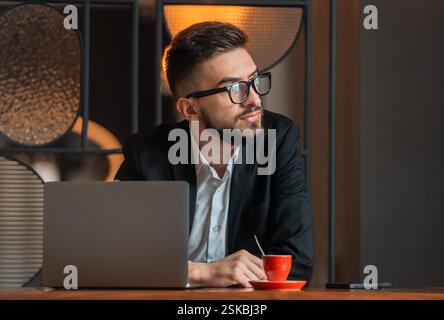 Ein junger Geschäftsmann, der wegschaut und im Büro nachdenkt. Stockfoto