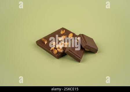 Milchschokolade und Haselnussstücke auf farbigem Hintergrund Stockfoto