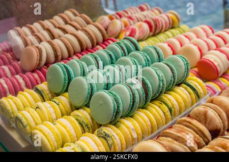 Nahaufnahme einer Reihe lebendiger französischer Macarons, die in einer Konditorei in Reihen angeordnet sind. Stockfoto