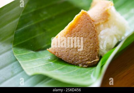 Traditionelles thailändisches süßes Menü, klebriger Reis mit Kürbispudding in Bananenblatt-Paket, natürliches Licht, Nahaufnahme des Essens, ausgewählter Fokus auf Kürbis-Cu Stockfoto