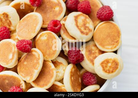 Köstliche frisch gekochte hausgemachte Mini Pfannkuchen mit Himbeeren. Trendiges Essen. Aussicht von oben. Frühstück für Kinder. Stockfoto