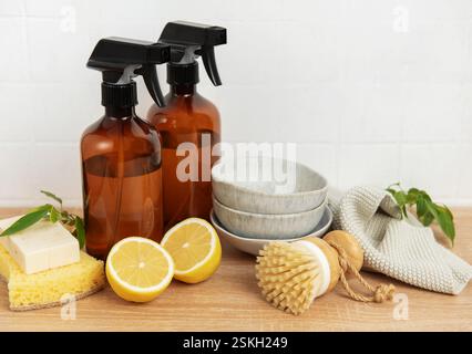 Natürliche Reinigungsmittel, Spülbürste, Zitronenhälften, Schwamm und Schüsseln, die auf einer Holzarbeitsfläche an der weißen Wand angeordnet sind Stockfoto