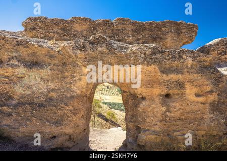 Ronda Stadt in Spanien. Steinbogen, der einen Blick auf die sonnenverwöhnte Landschaft bietet. Die antike Felsformation bildet einen natürlichen Rahmen für eine malerische Szene. Stockfoto