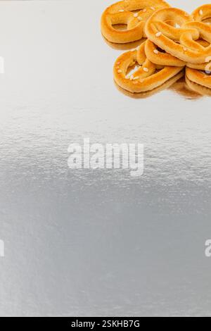Frisch gebackene weiche Brezeln sind ordentlich auf einer reflektierenden Oberfläche angeordnet. Ihre goldbraune Farbe und das Salz machen sie zu einem einladenden Imbiss für einen Stockfoto