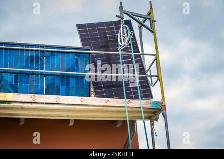 Installation von Solarpaneelen auf einem Dach. Sonnenkollektoren auf dem Dach. Arbeiter, die Solarzellen installieren. Stockfoto