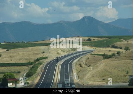 Autobahn. Fahrzeuge, die auf einer mehrspurigen Autobahn fahren, umgeben von sanften Hügeln und Bergen. Querformat. BULGARIEN Fortschritt, Konnektivität, wirtschaftliche Entwicklung Stockfoto