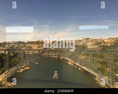Braga, Portugal. Ein faszinierendes Stadtbild entfaltet sich, zwei Brücken, die sich anmutig über einen pulsierenden Fluss bogen. Üppiges Grün umgibt die Ufer, während Boote tanzen Stockfoto