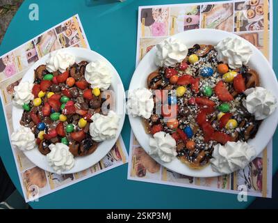 Zwei Teller Waffeln mit Schlagsahne, Erdbeeren, Schokoladensauce und bunten Süßigkeiten. Braga, Portugal. Süßes und köstliches Dessert. A Stockfoto